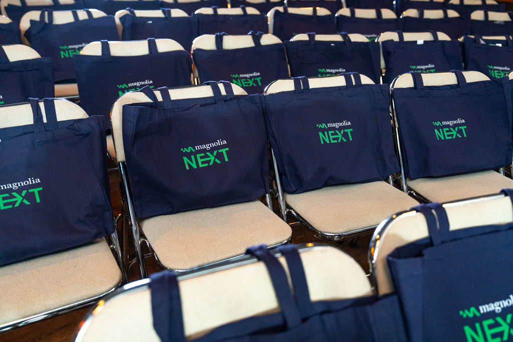 Magnolia NEXT branded tote bags laid out on seats, ready for attendees before the sessions begin